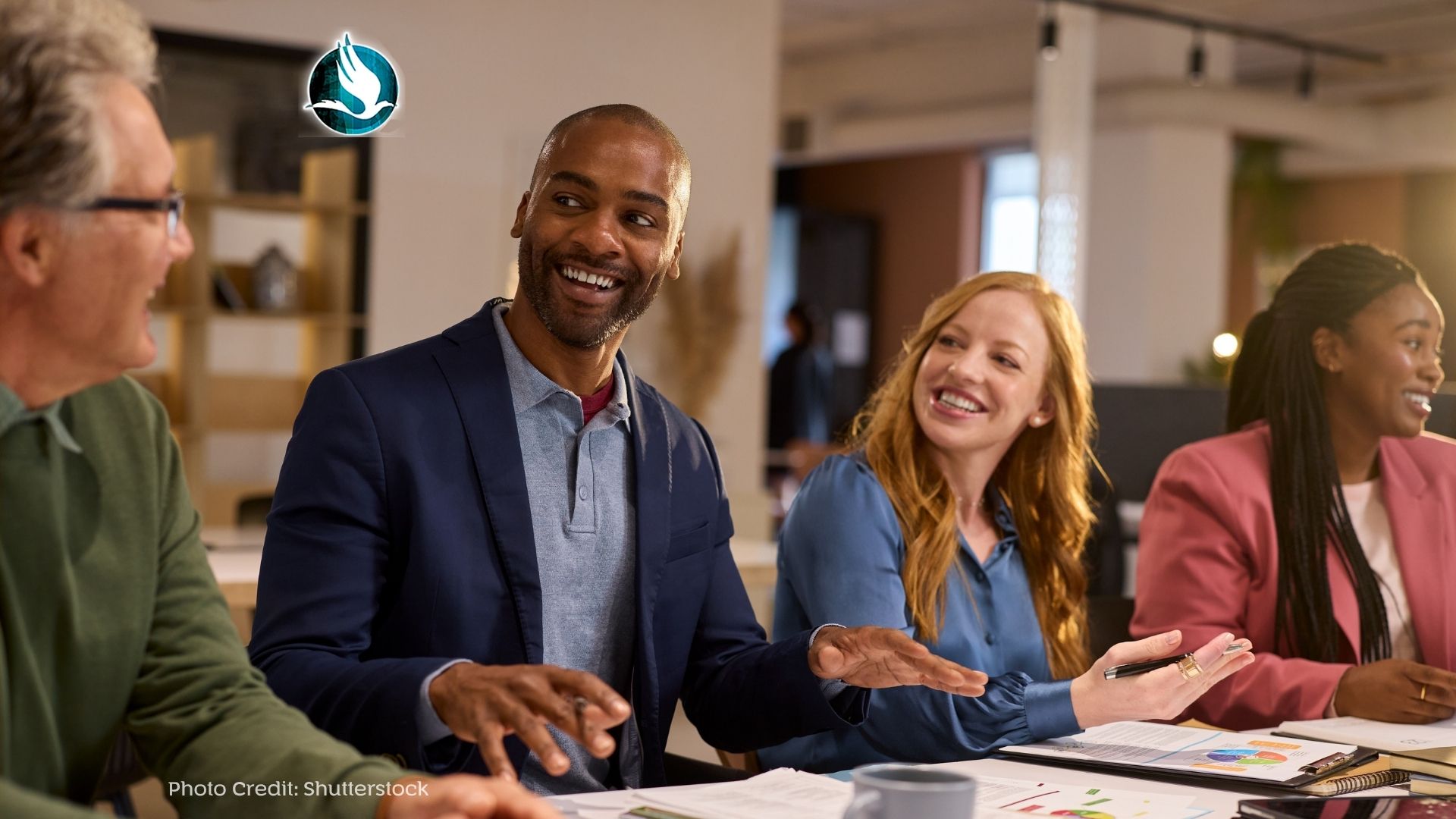 Happy leaders and team members at a meeting in modern office interior.