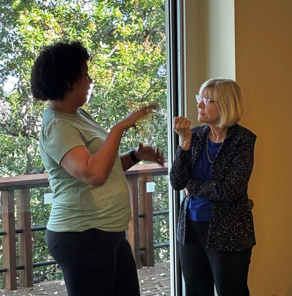 Two leaders in conversation near a window during a Thunderbird leadership engagement.