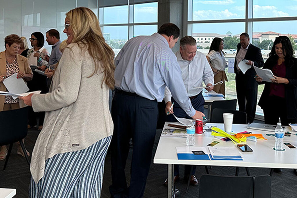 Leaders standing around a table during a facilitated group activity.
