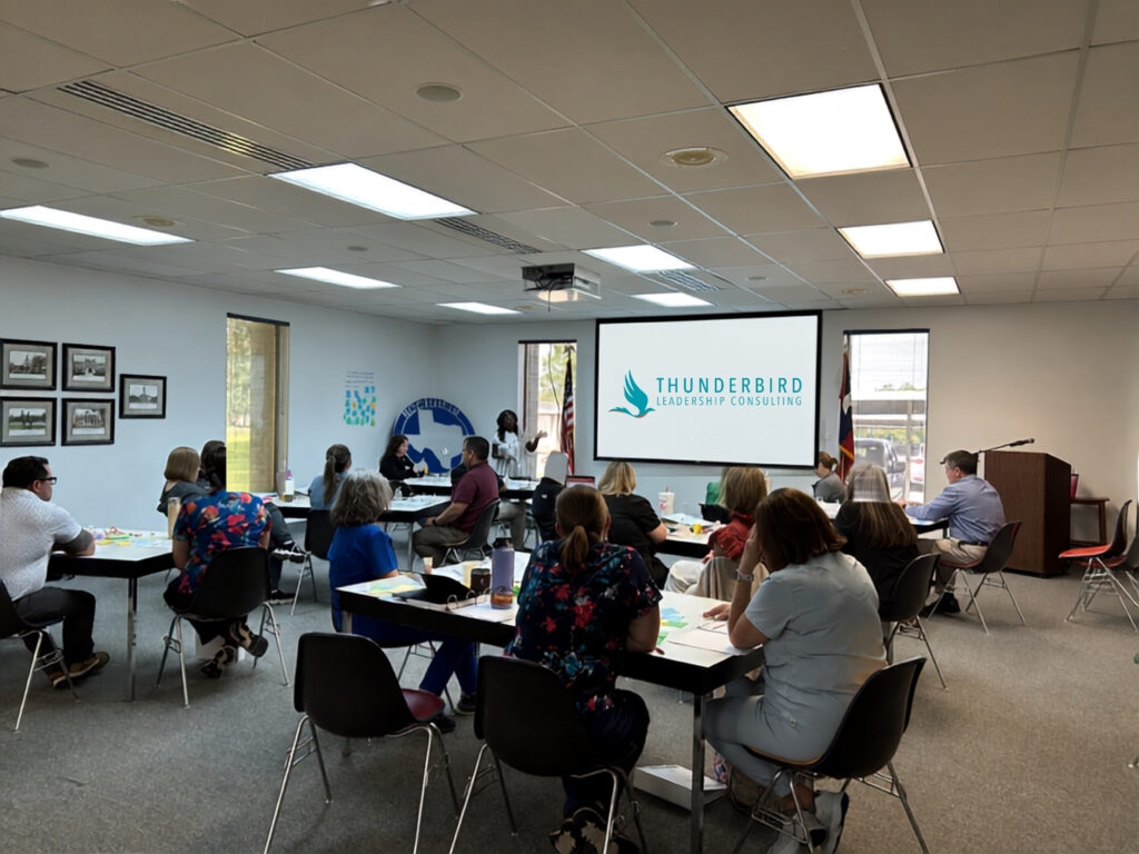 Leadership group participating in a facilitated workshop with a presentation screen in the room.