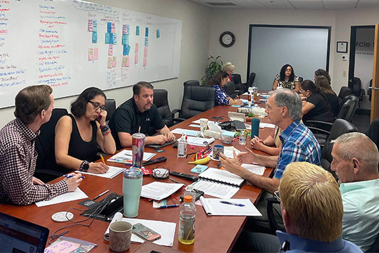Leadership team in discussion around a conference table during a facilitated working session.