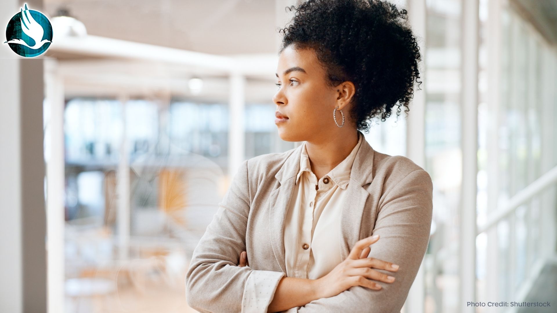 An african american female leader gazing thoughtfully with arms crossed.